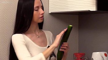 Jouer Femme brune met du lubrifiant sur un concombre pour bien glisser dans sa chatte